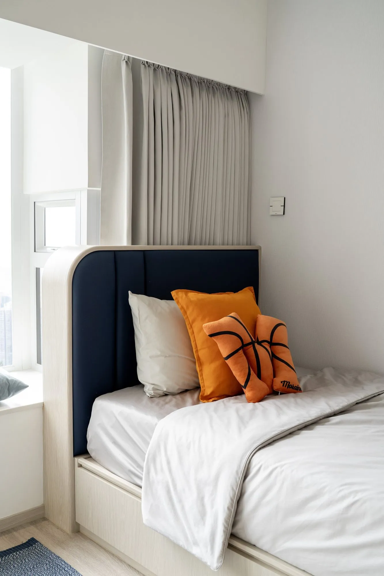 Child's bedroom by Artwill in a New Territories duplex, navy headboard with display niches and playful cushions